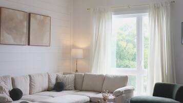 Un salon moderne avec un canapé d’angle, une table basse ronde et un ventilateur de plafond.
