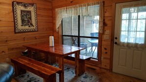 Ein Holzinnenraum mit Holztisch und -bänken, einem Spitzendeckengardine und einer Tür mit Fenster.