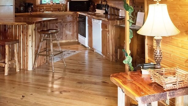 Ein rustikales Blockhaus-Interieur mit einer Holztreppe, einer Küchenzeile und einem Essbereich.