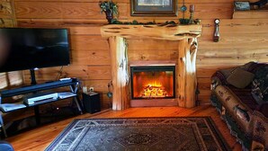 Ein gemütliches Wohnzimmer mit Kamin, Fernseher und einer Couch.