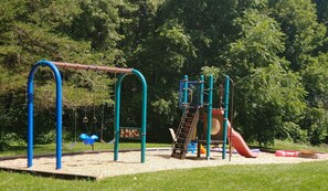En legeplads med gyngestole, rutchebane og klatrestrukturer.