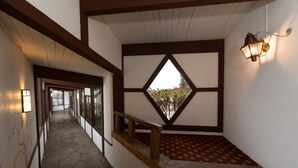 Un couloir au sol en pierre, avec des rampes en bois, une moquette à motifs et un décor mural géométrique.