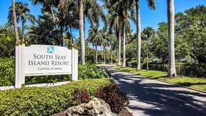 A sign for South Seas Island Resort in Captiva, Florida, with a pathway lined by palm trees and greenery.
