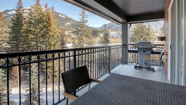 Een balkon met uitzicht op besneeuwde bergen en bomen.