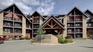 Een hotel met meerdere verdiepingen, een stenen gevel, balkons en een bord waarop staat Grande Rockies Resort.