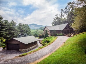 Une maison à deux étages avec une allée en gravier menant à un garage en bois.
