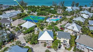 An aerial view of a residential area with houses, a tennis court, and a pool area.