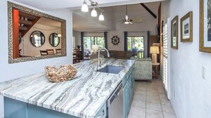 A kitchen with a marble countertop, a sink, and a ceiling fan.