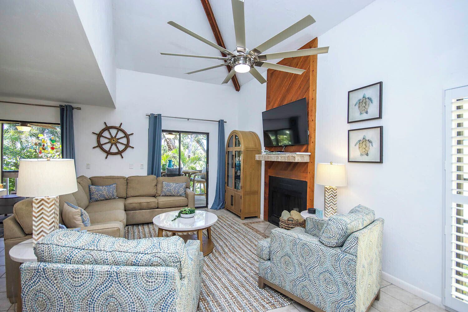 Un salon comprenant un canapé, des fauteuils, une table basse, un téléviseur, une cheminée et un ventilateur de plafond.