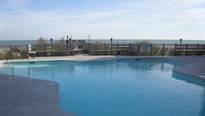 Una piscina con una marca de profundidad de 1.5 metros, rodeada por un deck de madera y vistas al océano.