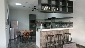 Une cuisine moderne dotée d’un îlot central, de tabourets de bar, d’une table à manger et d’un meuble à vin intégré.
