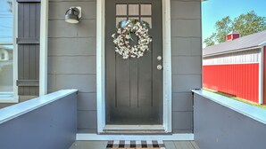 Una casa gris con una puerta blanca, un felpudo y un adorno de puerta.