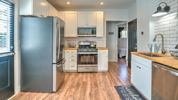 A modern kitchen with white cabinets, stainless steel appliances, and a wooden countertop. - 2UNITModernFarmhouse Sleeps13 (Lancaster)