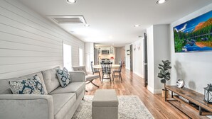A modern living room with a sofa, ottoman, and a dining area with a table and chairs. - 2UNITModernFarmhouse Sleeps13 (Lancaster)