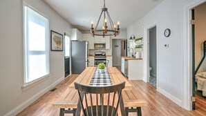 Una cocina moderna con armarios blancos, una isla central y una lámpara de araña.
