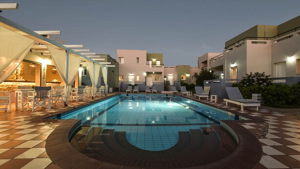 A swimming pool with lounge chairs and a bar area, surrounded by buildings with balconies. - Boutique studio for 2pers. (109) (Malia)