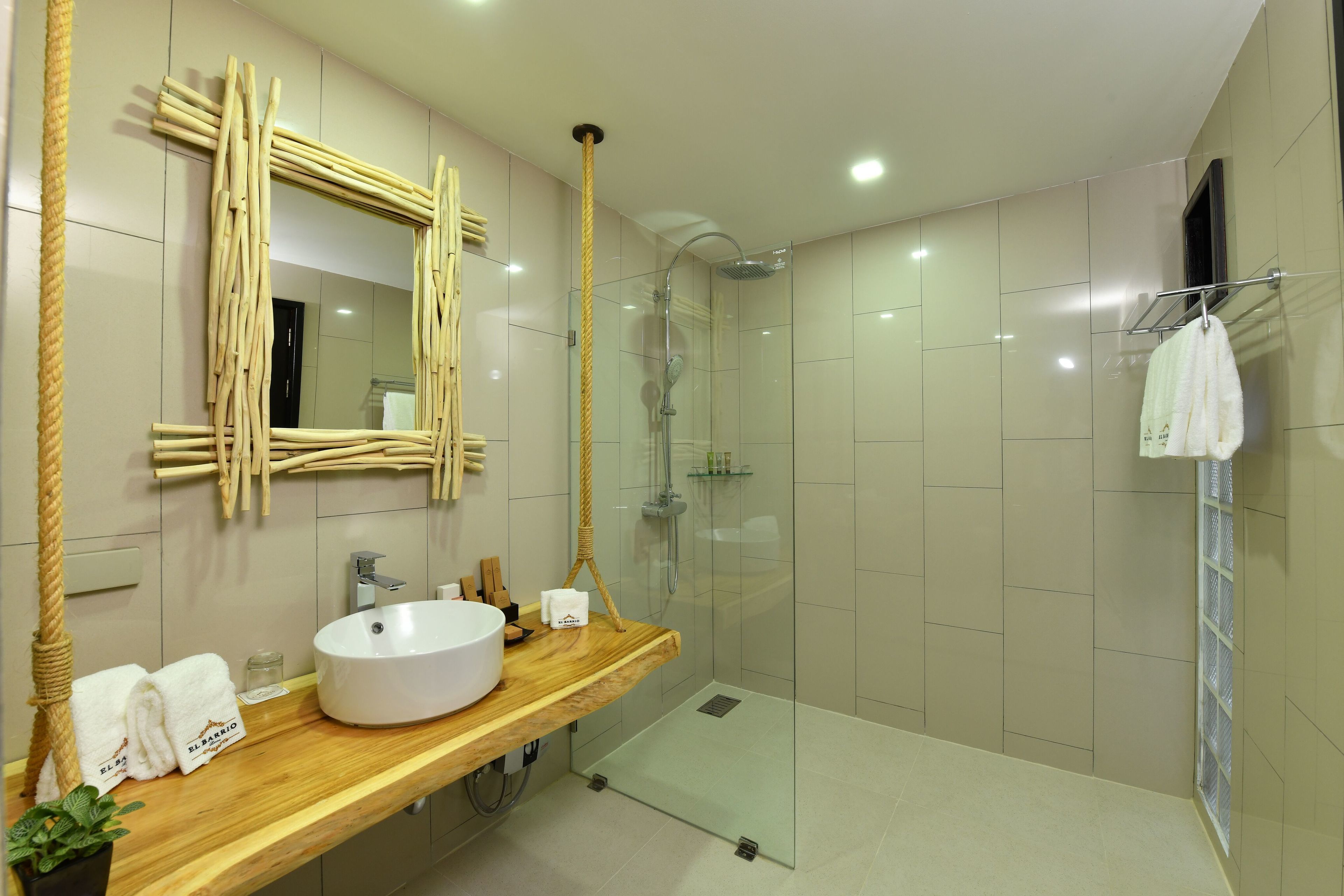 A modern bathroom with a wooden vanity, a large mirror, a glass shower enclosure, and a towel rack.