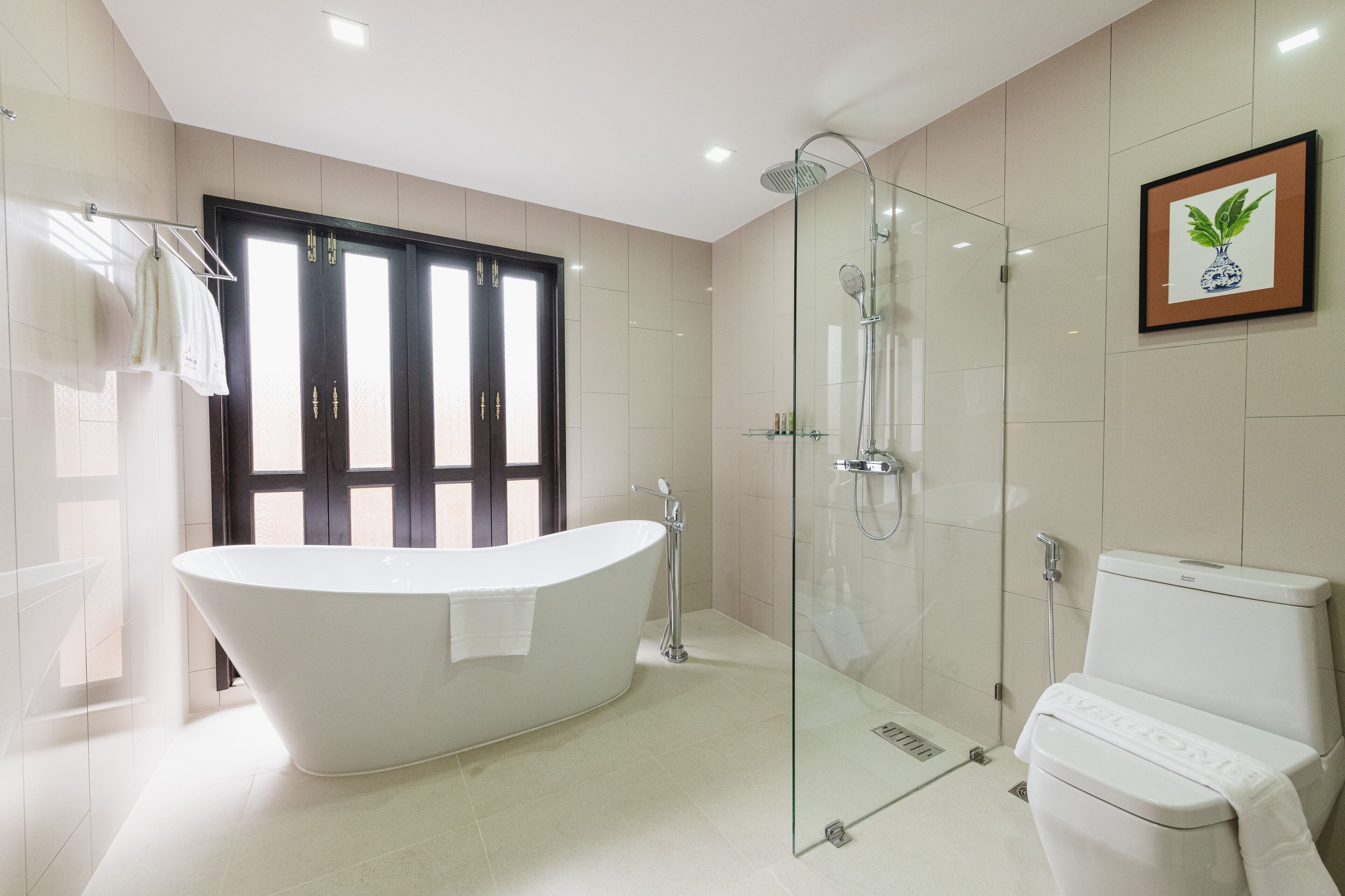 Un baño moderno con una bañera independiente, ducha con mampara de vidrio y un inodoro.