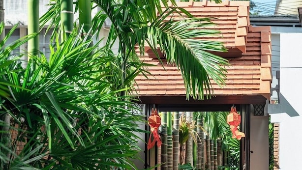 A serene waterway with lush greenery and a traditional building with a tiled roof. - El Barrio Lanna (Chiang Mai)