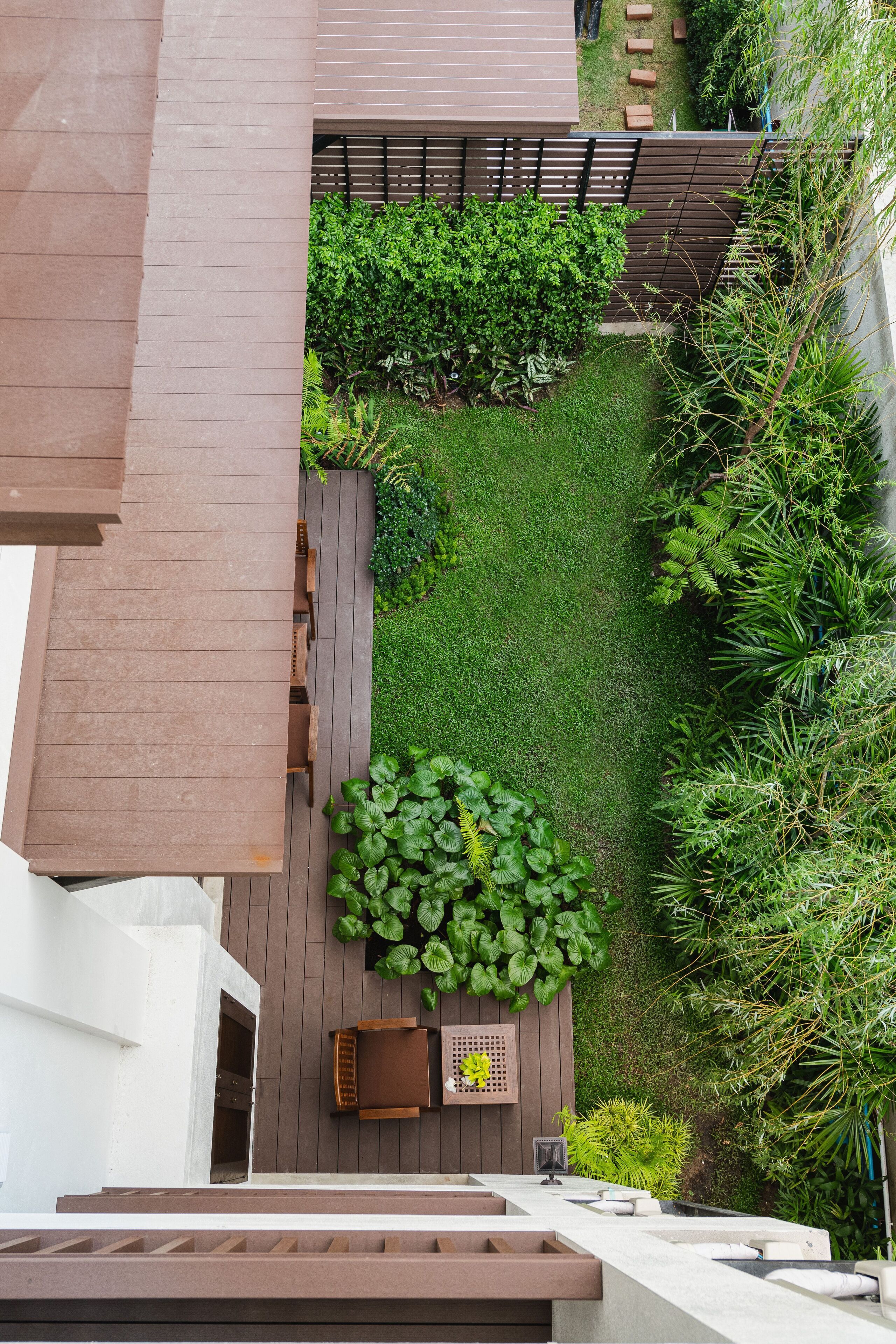 Un jardin sur le toit doté d’une terrasse en bois, d’un espace salon et d’une végétation luxuriante.