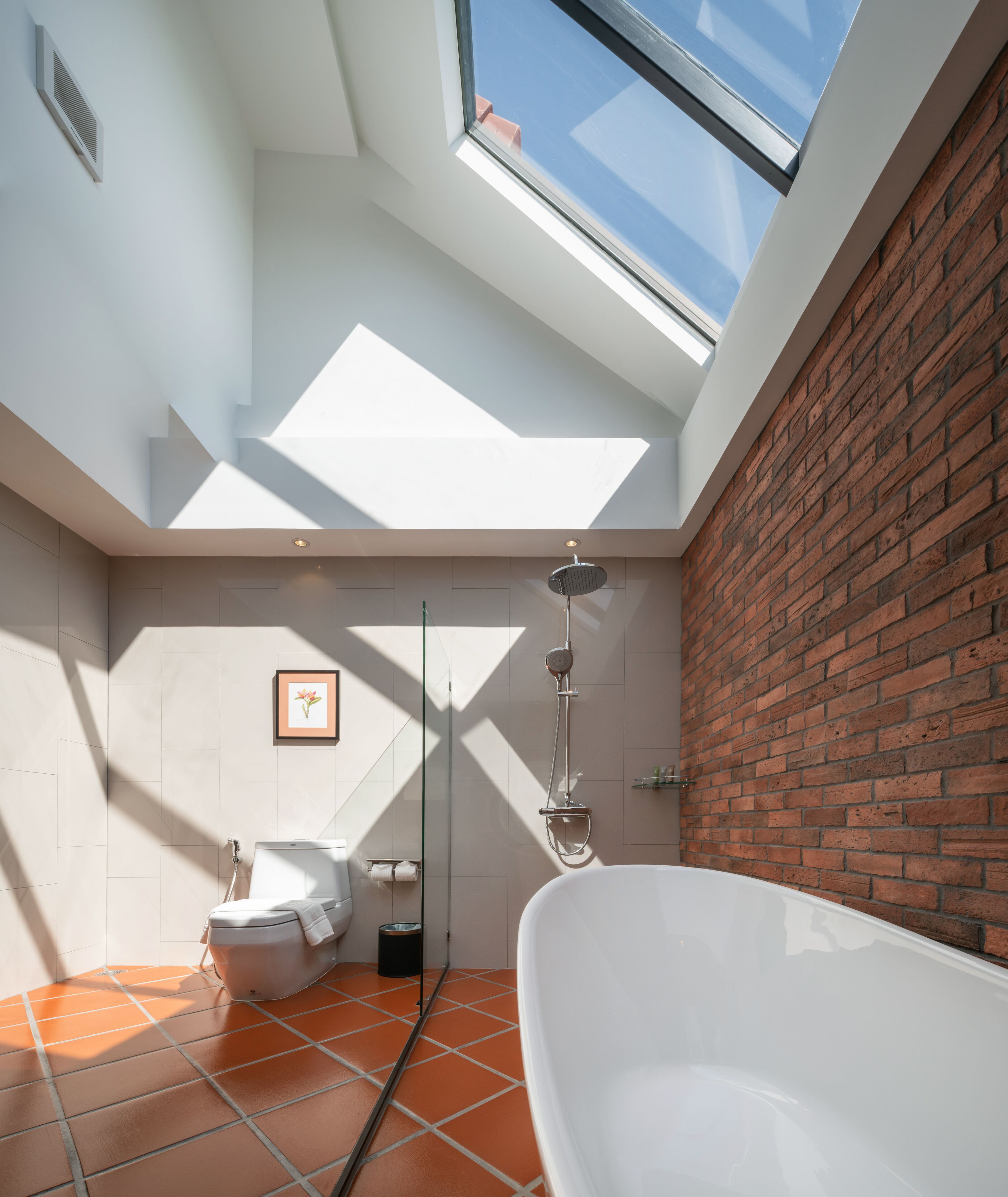 Un baño moderno con tragaluz, una bañera independiente y una ducha.