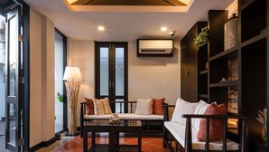 A modern living room with a high ceiling, a sofa set, a coffee table, and a bookshelf. - El Barrio Lanna (Chiang Mai)
