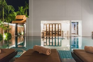 A poolside area with lounge chairs and a wooden structure.