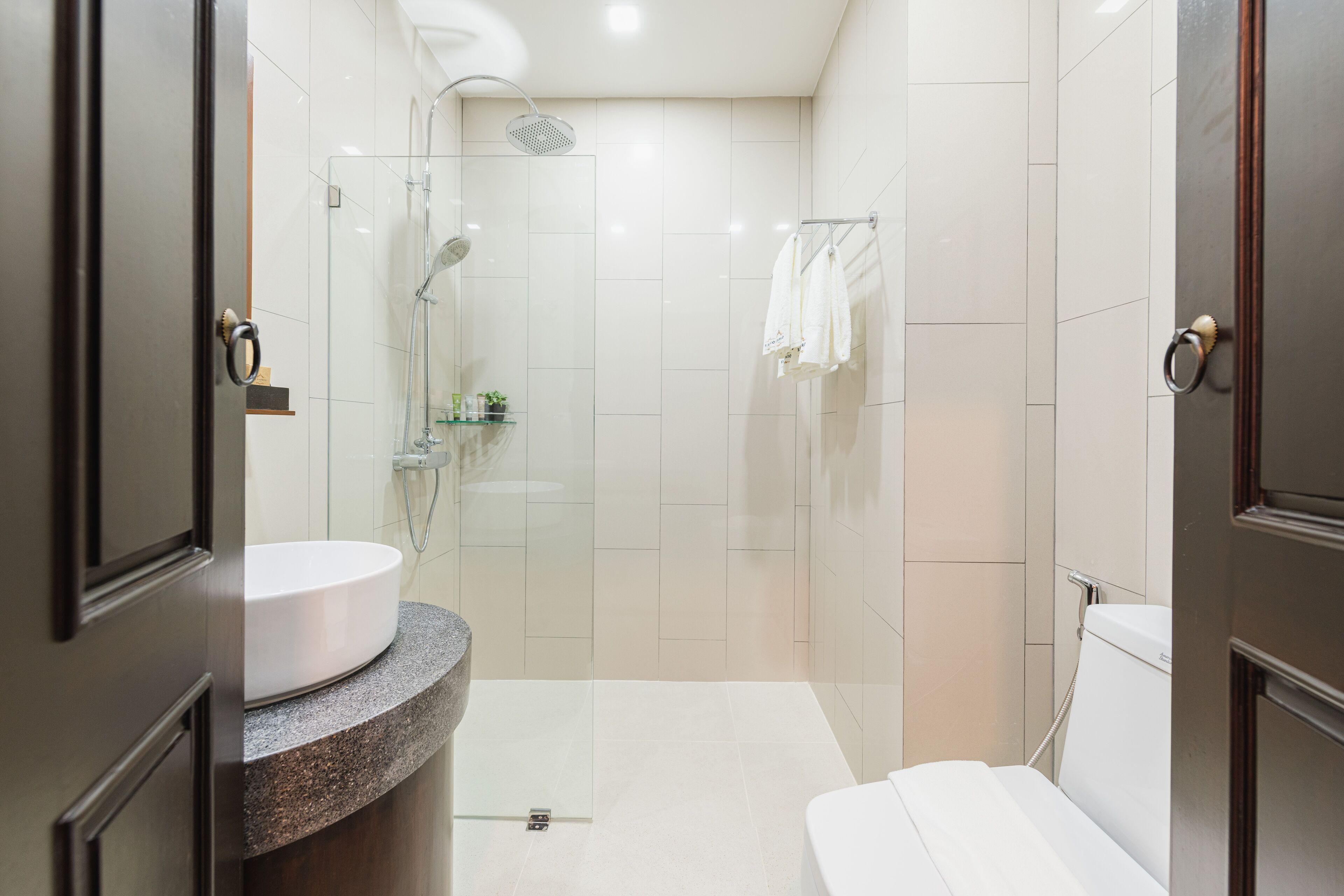 A modern bathroom with a glass-enclosed shower, a white sink, and a toilet.