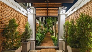 A brick pathway flanked by planters with greenery, leading to a covered entrance with a lantern. - El Barrio Lanna (Chiang Mai)