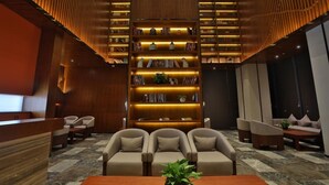 A modern lobby with a central seating area, a large bookshelf, and a reception desk. - SSAW Boutique Wenzhou Meimei Square Hotel (Wenzhou)