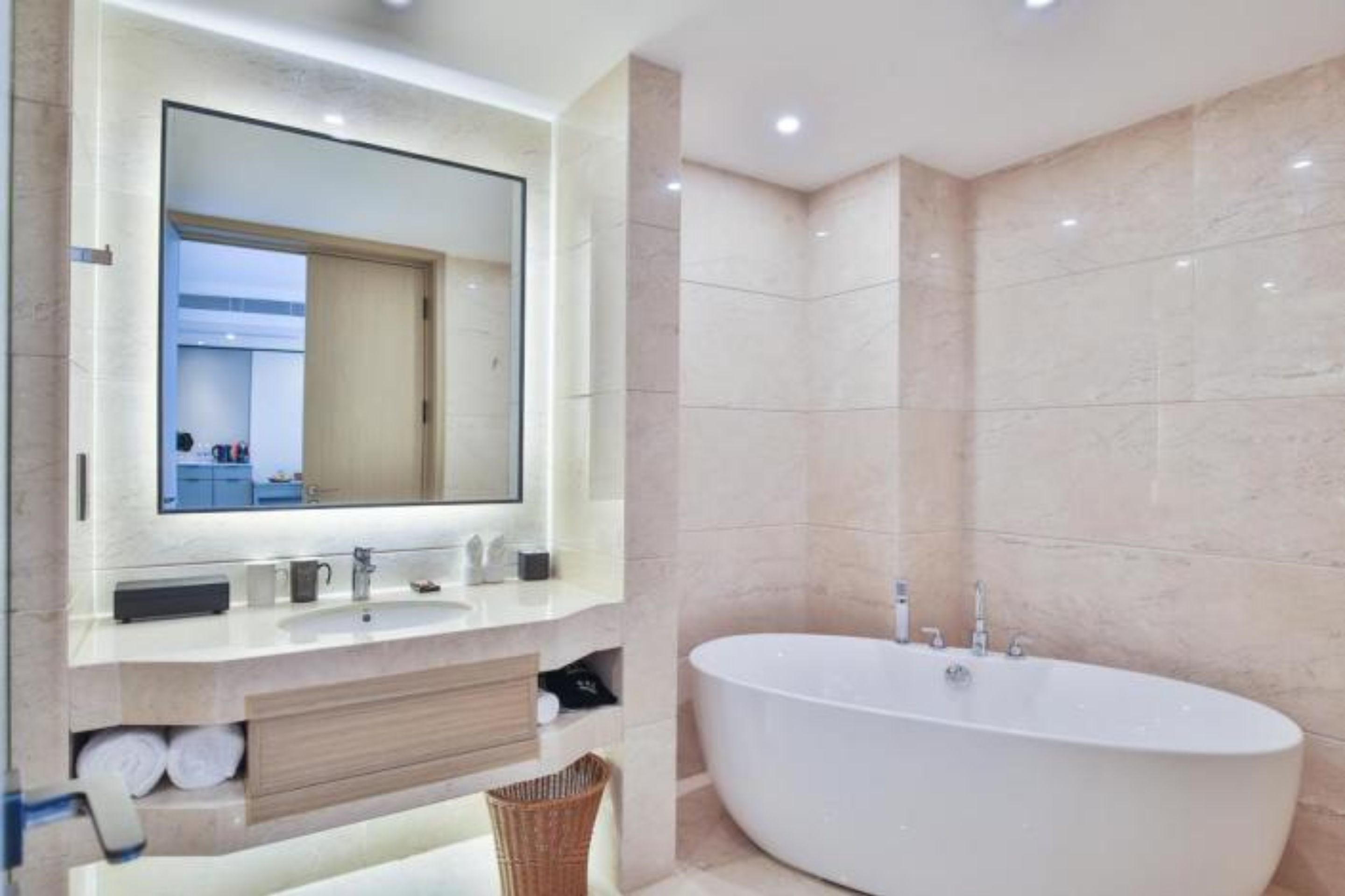Un baño moderno con una bañera independiente, un espejo grande y un lavabo con espacio de almacenamiento.