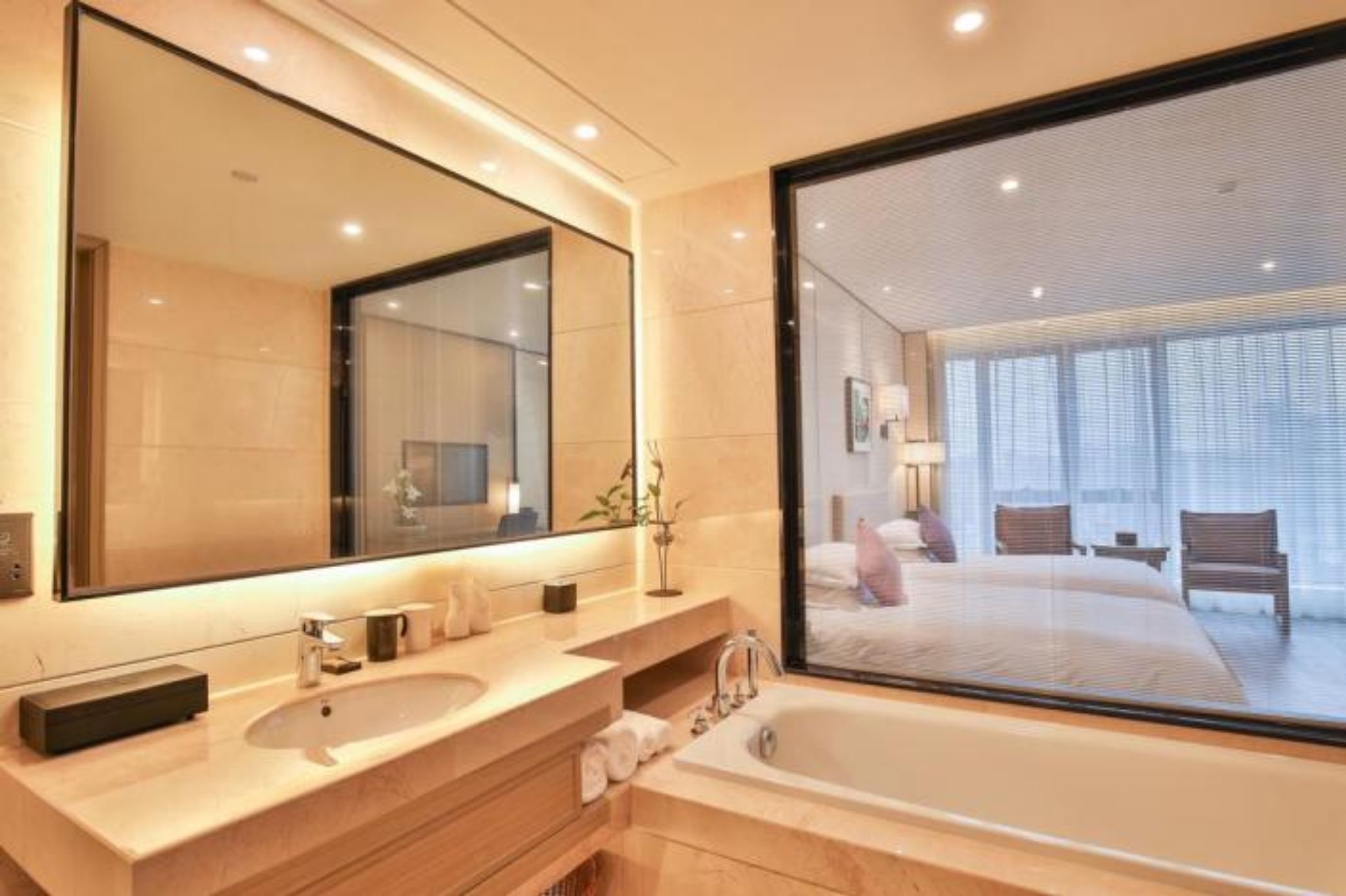 Une salle de bain moderne avec un grand miroir, une baignoire et une grande fenêtre.