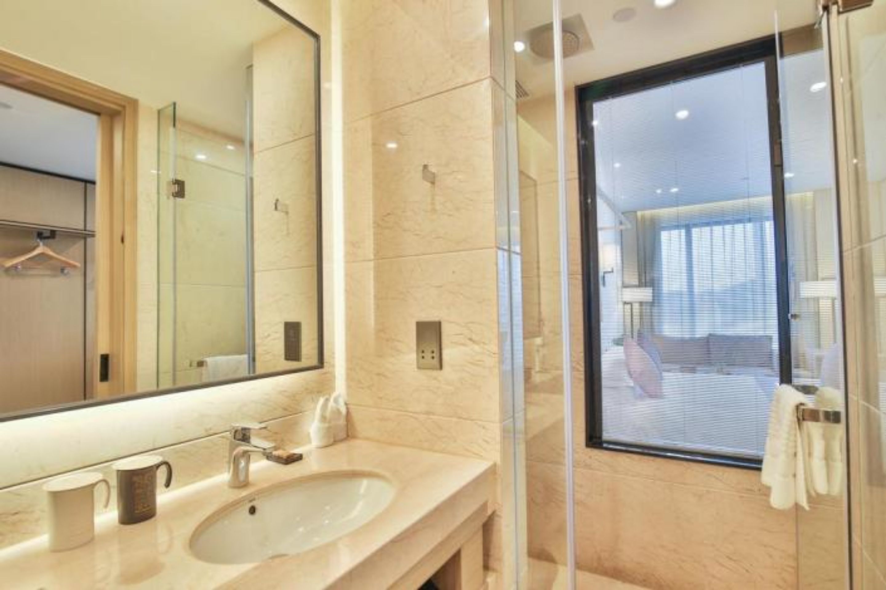 A modern bathroom with a large mirror, a sink, and a glass shower enclosure.