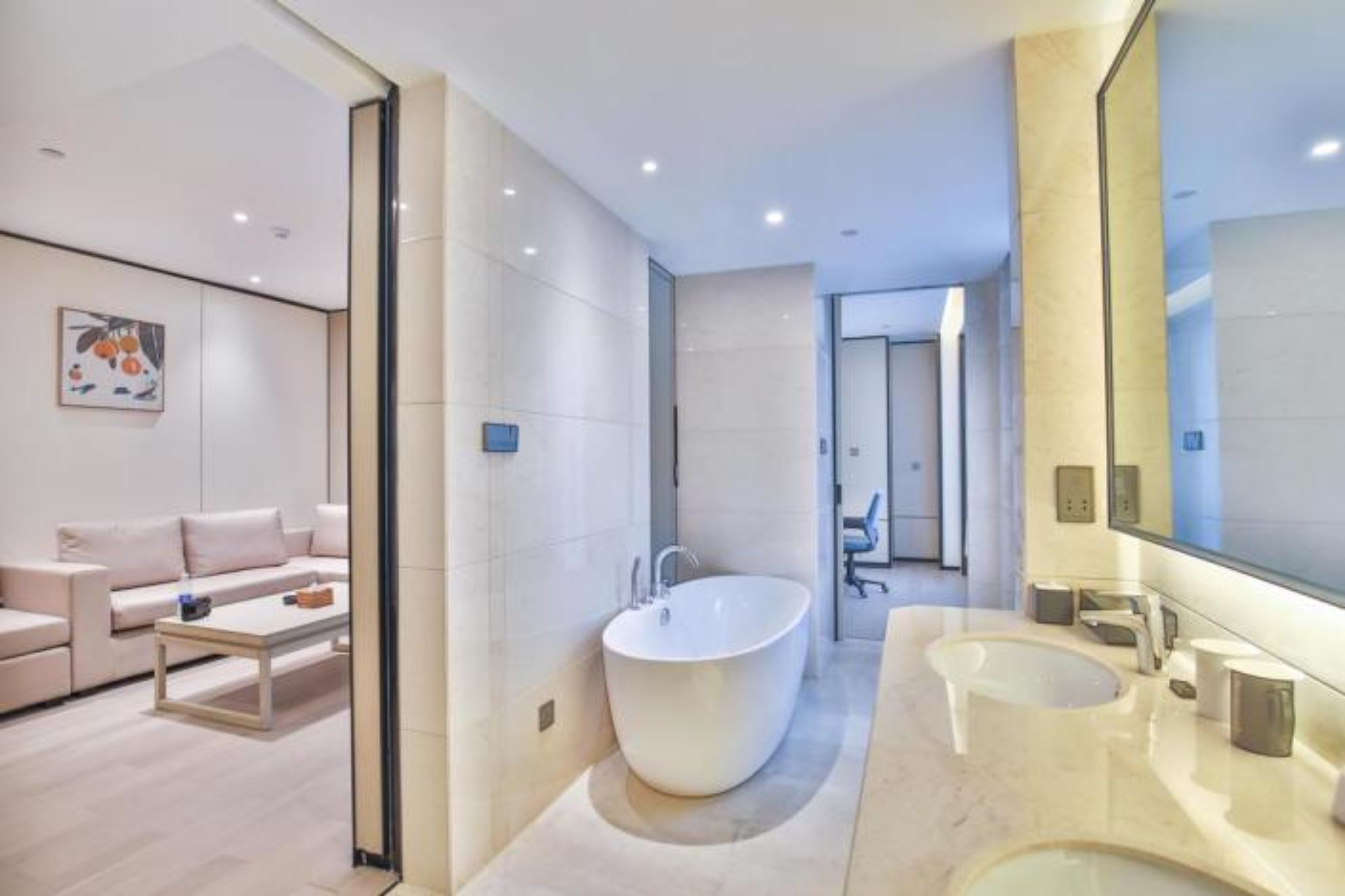 Un baño moderno con una bañera independiente, dos lavamanos y un espejo grande.