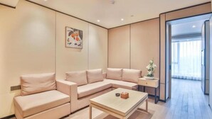 A modern living room with a beige sofa, a wooden coffee table, and a small side table with a plant. - SSAW Boutique Wenzhou Meimei Square Hotel (Wenzhou)