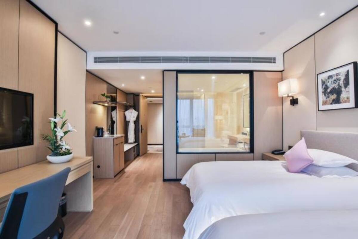 A modern hotel room with a bed, desk, and a walk-in closet.