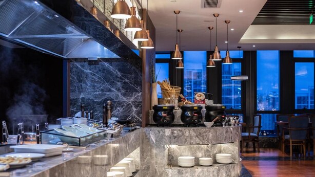 A modern kitchen with a marble countertop, stainless steel appliances, and copper pendant lights. - SSAW Boutique Wenzhou Meimei Square Hotel (Wenzhou)