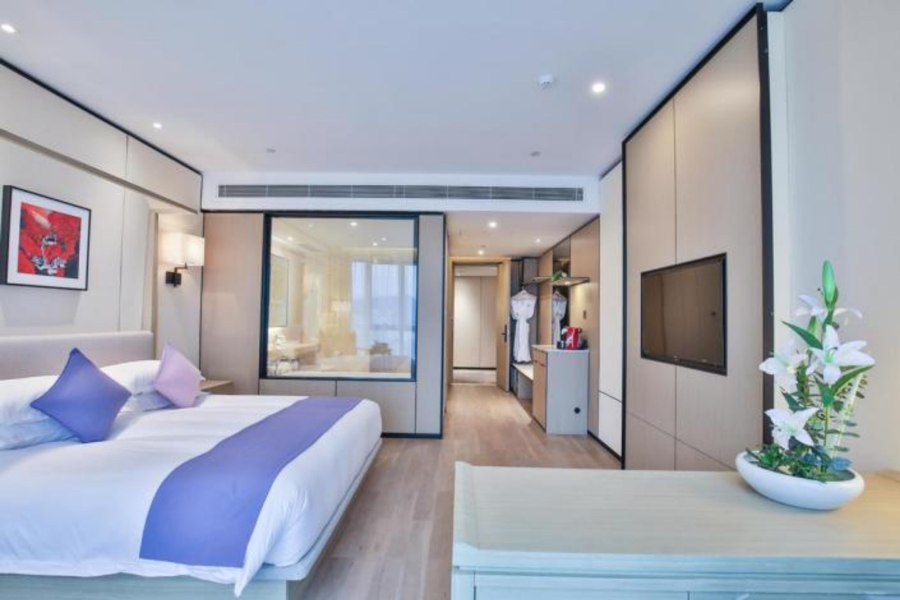 Quarto de hotel moderno com cama, mesa de cabeceira e uma janela grande.