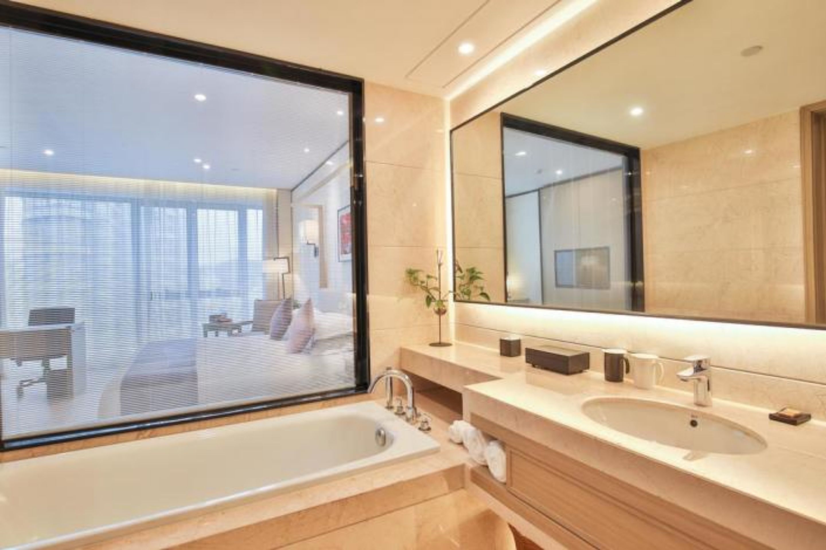 A modern bathroom with a large window, a bathtub, and a vanity with a mirror.