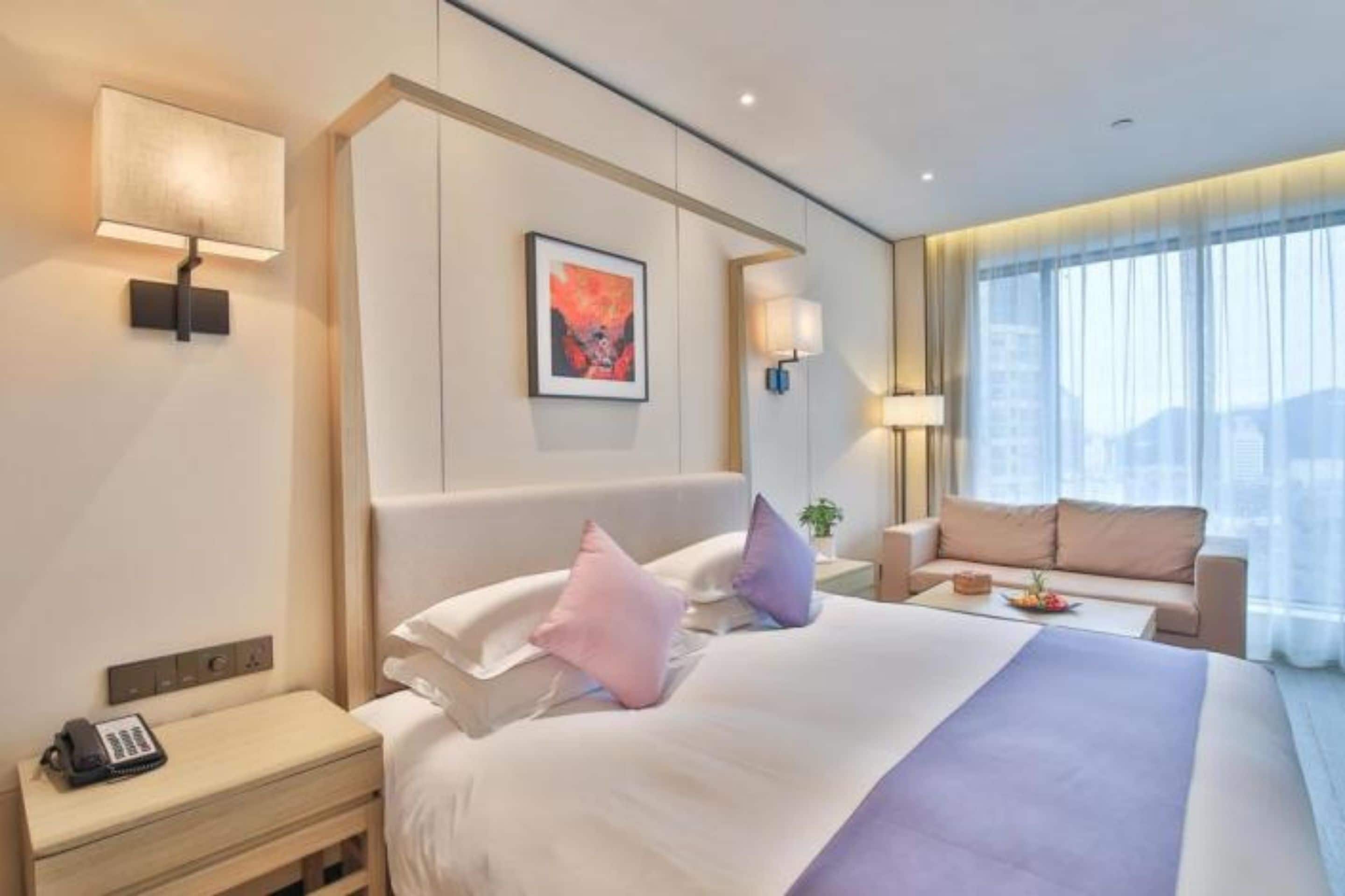 Habitación de hotel con una cama grande, mesitas de noche, un escritorio, una silla y ventana con vistas.