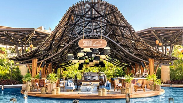 Un espace piscine doté d’un coin salon abrité et d’un panneau indiquant « Shore Club ».
