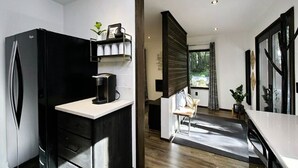 Una cocina moderna con un refrigerador negro, una encimera blanca y una zona de comedor de madera.