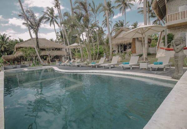 Una piscina al aire libre, sombrillas, sillones reclinables de piscina