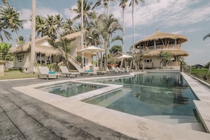 Una piscina al aire libre, sombrillas, sillones reclinables de piscina