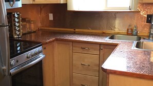 A kitchen with wooden cabinets, a stove, and a sink. - Alaskan Adventure Cabin (Sterling)