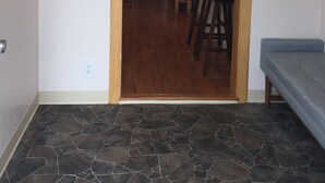 A room with a wooden door leading to a staircase, a television mounted on the wall, and a bench. - Alaskan Adventure Cabin (Sterling)