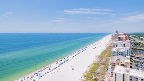 Une plage bordée d’une rangée de parasols et d’une rangée de bâtiments le long du rivage.