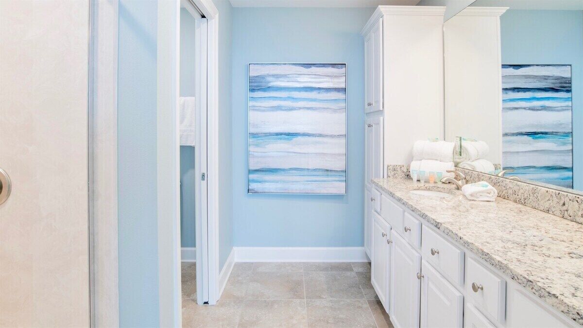 A bathroom with a blue wall, a large mirror, and a countertop with towels.