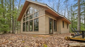 A cabin with large windows, surrounded by trees.
