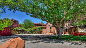 A residential area with a gravel driveway, a large tree, and a red building with a brick facade.